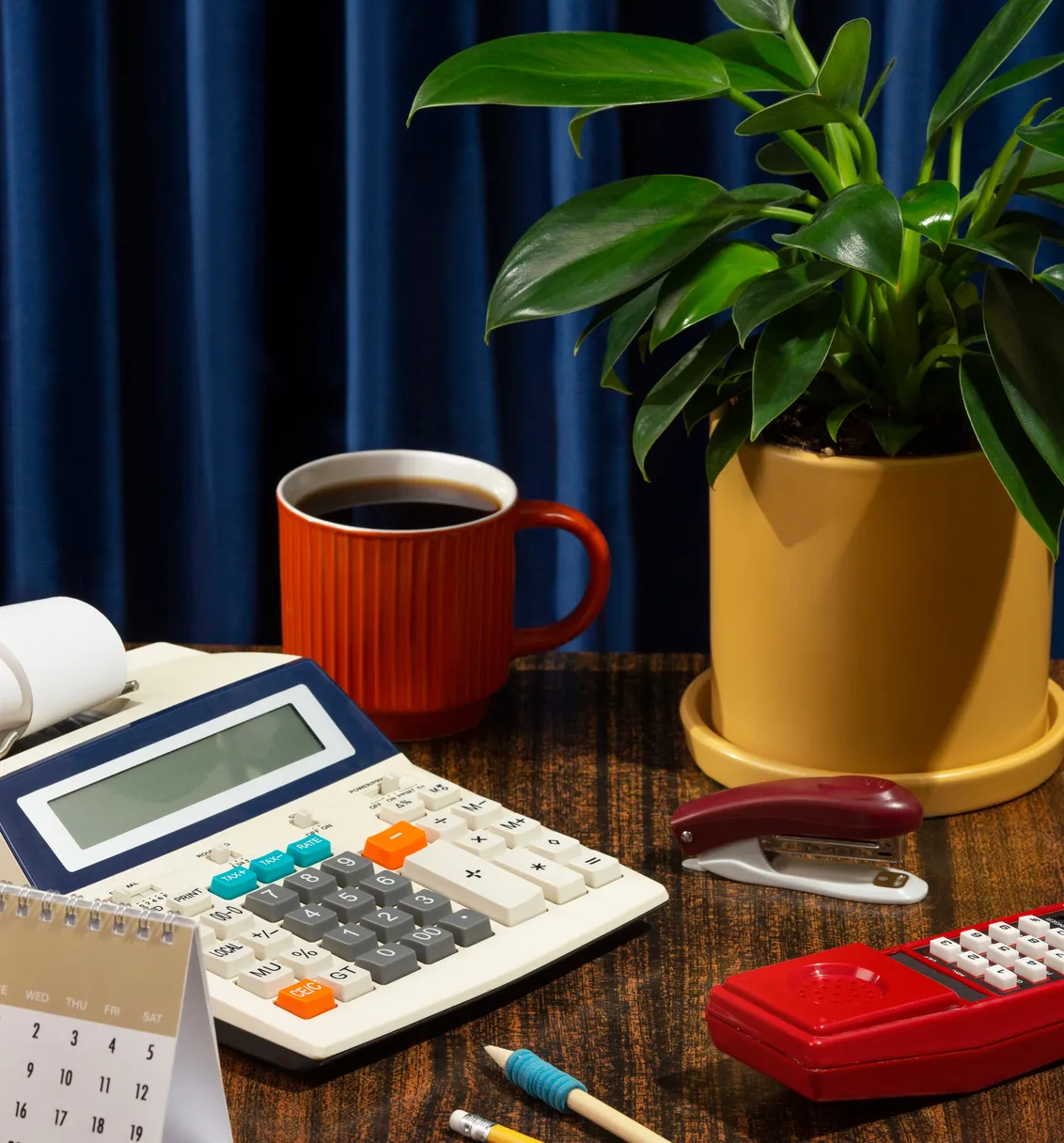 Desk with a calculator, coffee, and a plant